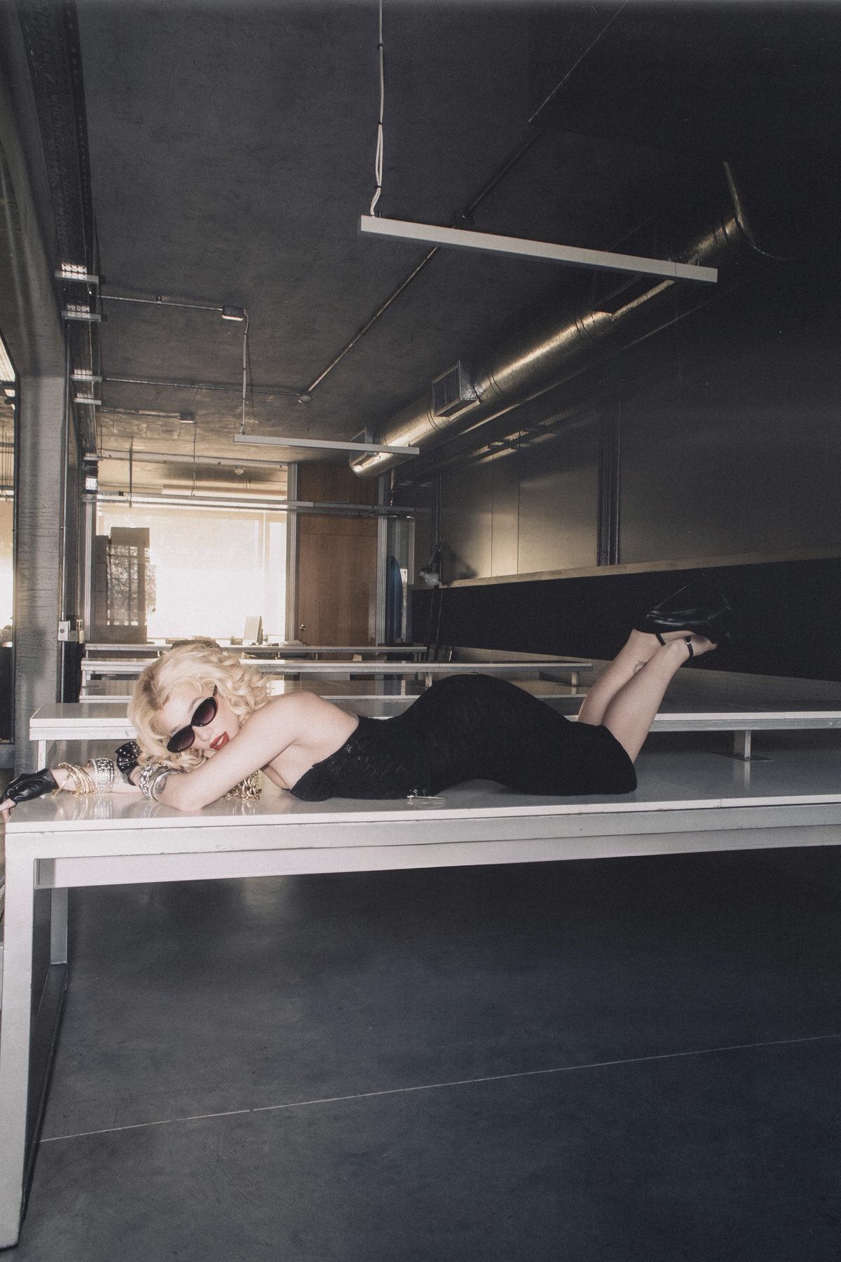 Wide shot of Ángela Torres resting on a desk in a concrete office