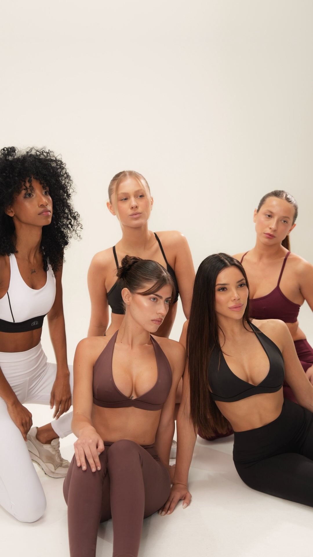 Five models in Eiloa activewear seated on a white studio floor