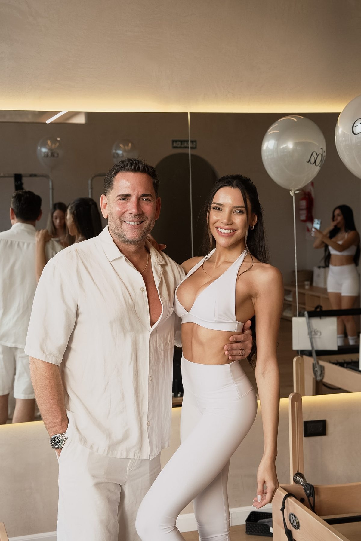 Host with a guest in a white linen shirt, Eiloa balloons behind
