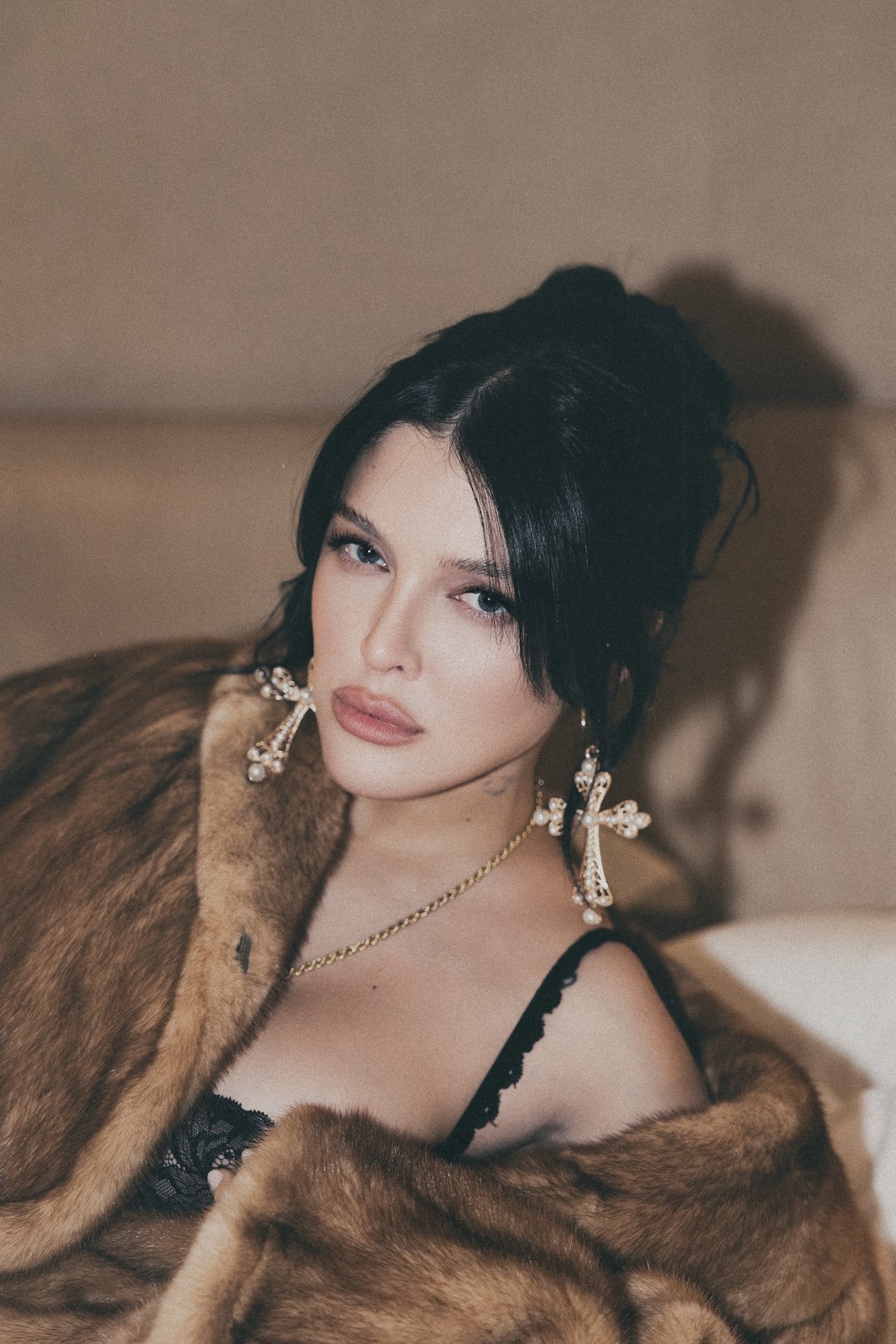 Close portrait of Sofía Gonet with pearl cross earrings and a mink collar