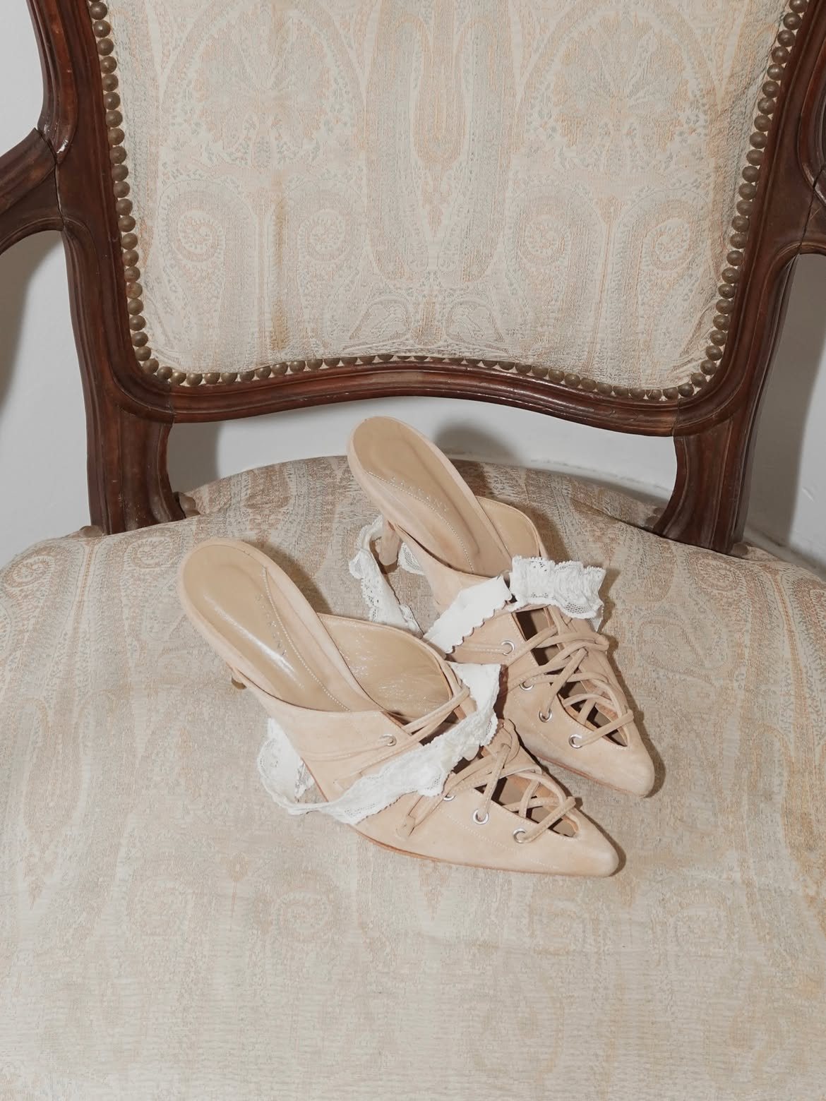 Laced nude mules and a lace garter on an antique armchair