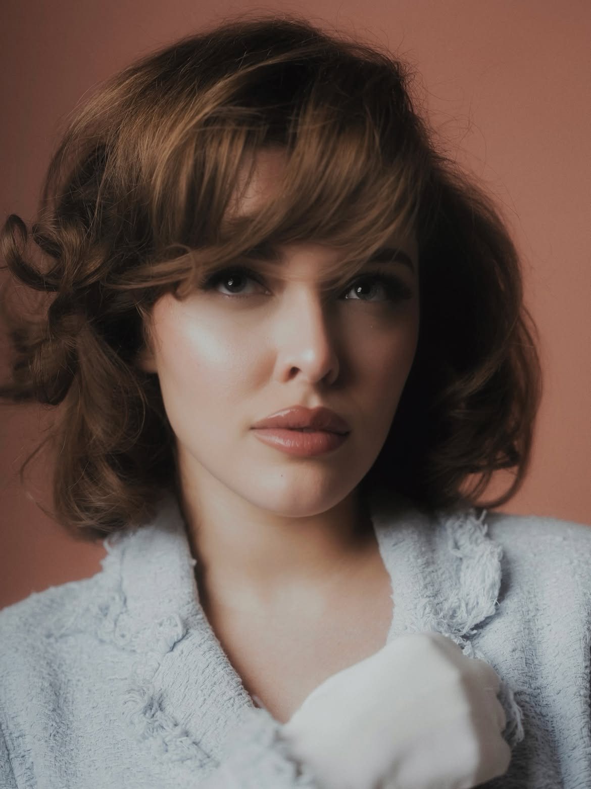 Portrait of Sofía Gonet in a pale blue tweed jacket on terracotta