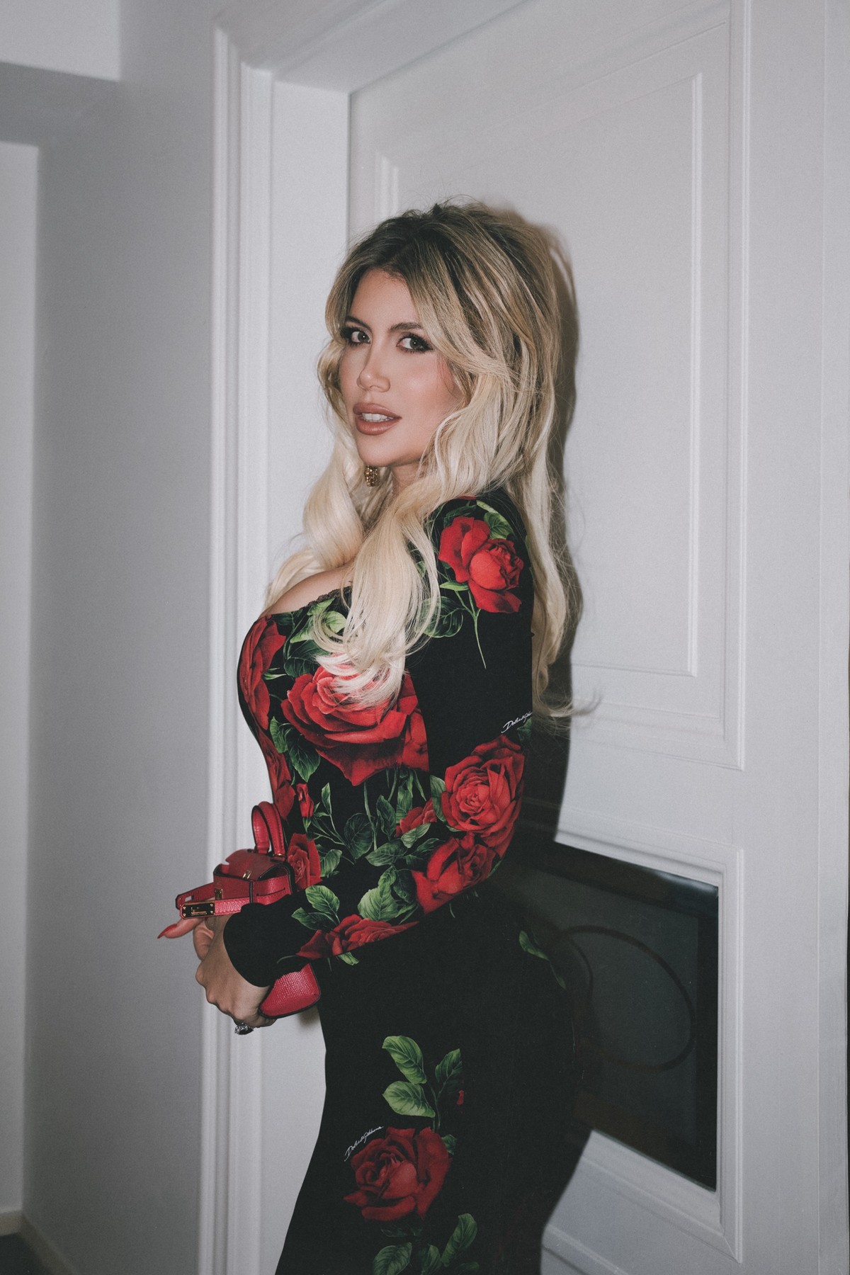 Wanda Nara in profile, looking back over her shoulder by a white door